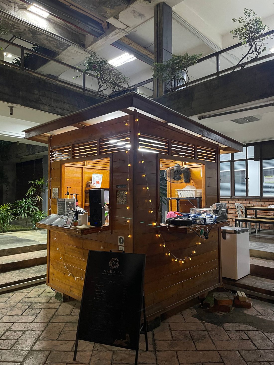 The Sarang wooden kiosk booth lit up with string lights at night